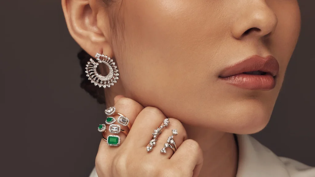Model wearing diamond jewellery designed and manufactured by El Galla. She is wearing one diamond ring, another emerald ring and a diamond earring.
