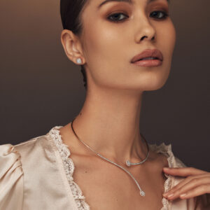 Elegant slim yellow gold open necklace featuring two diamond accents on each end and a rose gold diamond earring