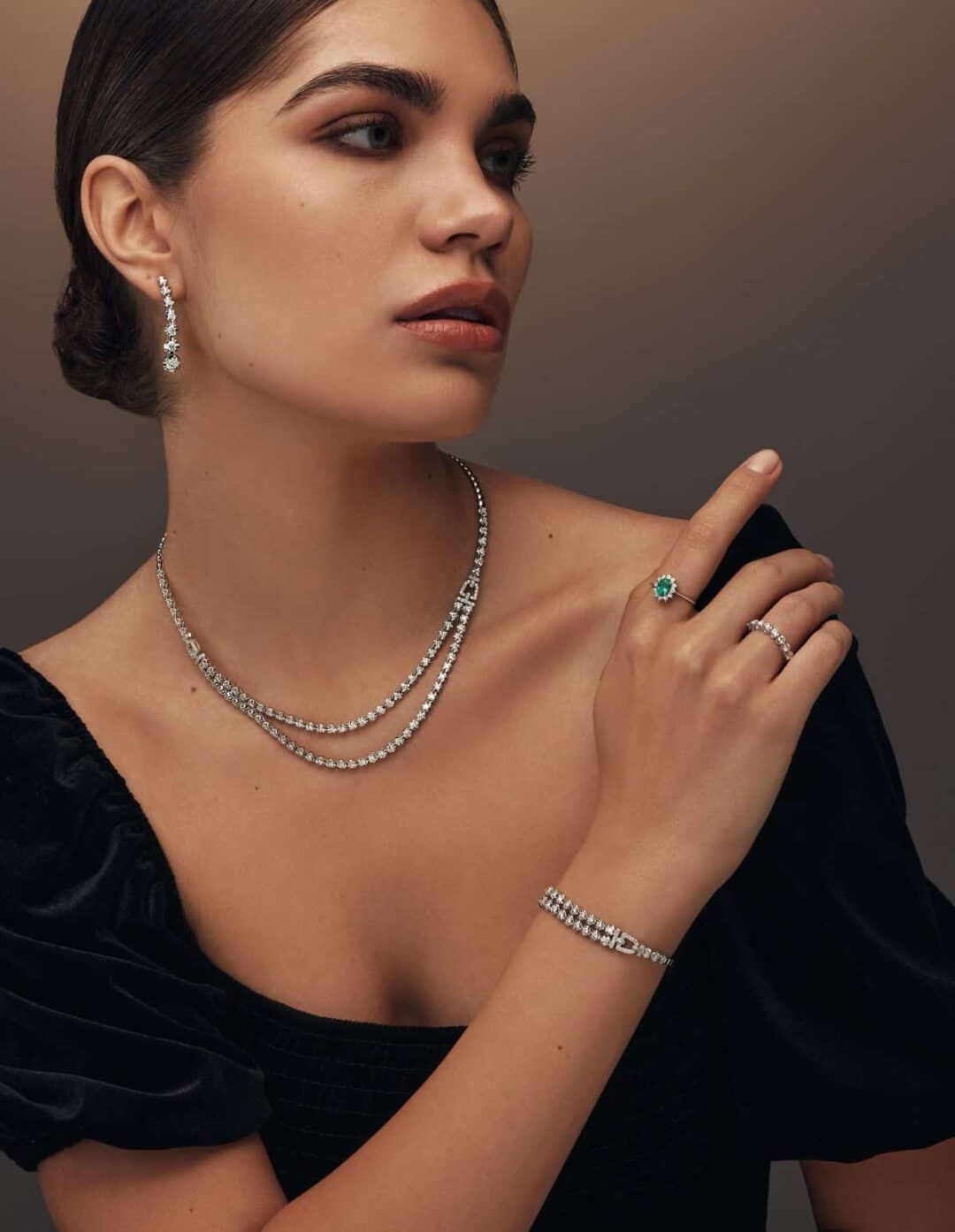 model wearing double diamond tennis necklace and Minimalist white gold ring featuring a single emerald gemstone in the center by el galla gold and diamond brand