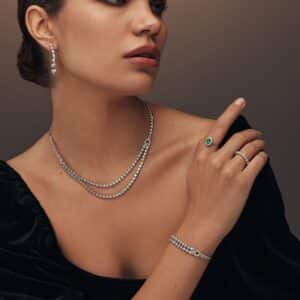 model wearing double diamond tennis necklace and Minimalist white gold ring featuring a single emerald gemstone in the center by el galla gold and diamond brand